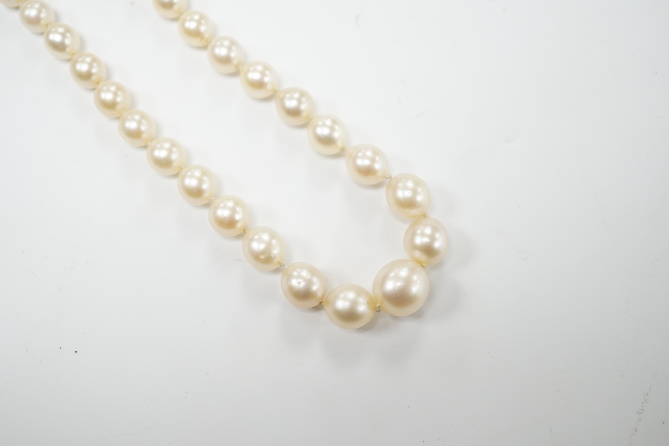 A single strand graduated cultured pearl necklace with millegrain set diamond cluster and yellow metal clasp, 40cm.